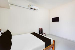 Dieses weiße Zimmer verfügt über ein Bett und einen TV. in der Unterkunft Super Collection O Sholinganallur Chennai Formerly Nimalan Residenc in Chennai