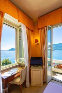 ein Zimmer mit Schreibtisch, Tisch und Fenstern in der Unterkunft LVG Hotel Collection - Pallanza in Verbania
