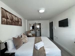a bedroom with a white bed and a television at The 37 Suites in Ponders End