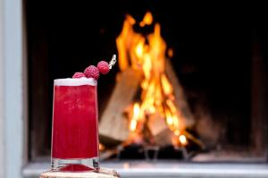 a red drink with raspberries in front of a fireplace at Hôtel Jules & Jim in Paris