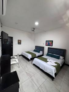 two beds in a room with a tv and a couch at Hotel Sion Real in Neiva