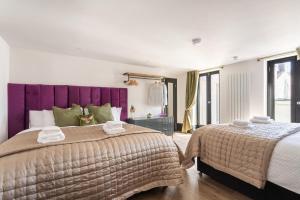 a bedroom with two beds and a purple headboard at Fun Kemptown Stay with Games Close To Seafront in Brighton & Hove