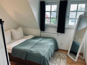 a small bedroom with a bed and two windows at Haus Lykkelig in Zingst