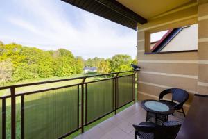 a balcony with two chairs and a view of the woods at Peaceful Apartment Wrzosowo Bay with Parking by Noclegi Renters in Wrzosowo