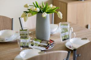 a wooden table with a vase with flowers and glasses at Peaceful Apartment Wrzosowo Bay with Parking by Noclegi Renters in Wrzosowo