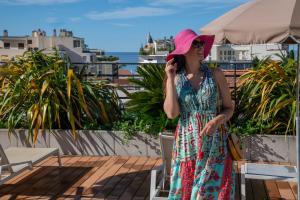 a woman in a dress and pink hat talking on a cell phone at Best Western Premier Le Patio des Artistes Wellness Jacuzzi in Cannes