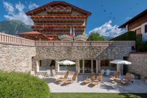 grupa krzeseł i parasoli przed budynkiem w obiekcie Beverly Alps Hotel & Spa w mieście Pinzolo