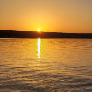 a sunset over a body of water with the sun setting at Apartman Dunja in Gornji Karin