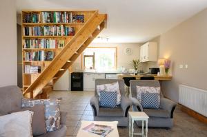 a living room with two chairs and a book shelf with books at The Hut at Baywatch Bed & Breakfast in Renvyle