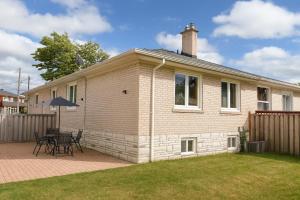 a house with a patio and a table in the yard at Newly Renovated 3BR North York Bungalow with Backyard Patio & Volleyball Set! Close to Rogers Stadium, TTC Subway Access, Perfect for Family Travel, Group Trips or Work Stays! in Toronto