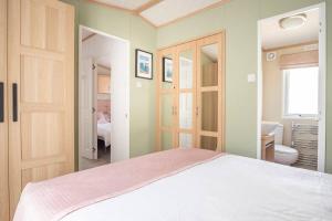 a bedroom with a white bed and a bathroom at The Woodlark in Poole