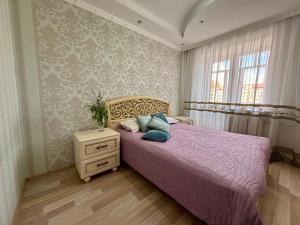 Un dormitorio con una cama morada con una colcha morada. en Квартира, en Astana