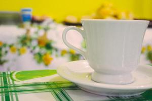 a white coffee cup sitting on a plate on a table at Hotel Santo Antoninho in Goiânia
