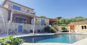 a swimming pool in front of a house at Le Mas du Grand Chêne - Chambres & Roulotte in Nyons