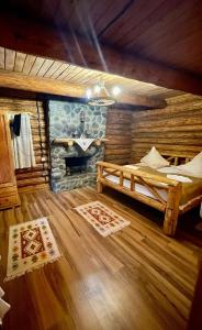 a bedroom with a fireplace in a log cabin at Cabana Wiarusti in Moieciu de Sus