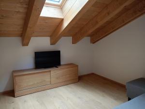 a room with a flat screen tv on a wooden cabinet at Tre Cime Apartments - monolocali in Auronzo di Cadore