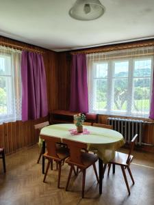 a dining room with a table and chairs and windows at Sielankowy Domek in Istebna