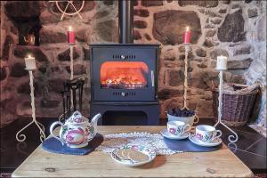 a wooden table with tea sets and a stove at Betws Bach in Criccieth +4 photos