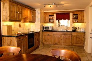 a kitchen with wooden cabinets and a table with chairs at Betws Bach in Criccieth