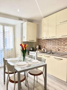 a kitchen with a white table with chairs and flowers at La Torretta Apartment in Savona