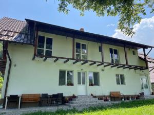 una gran casa blanca con sillas y mesas en La Moieciu pe Deal, en Moieciu de Jos