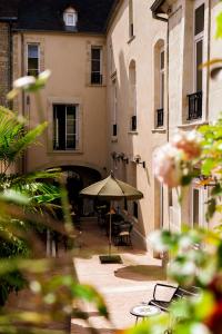 un patio extérieur avec un parasol, des chaises et des tables dans l'établissement Hôtel La Particulière, à Caen