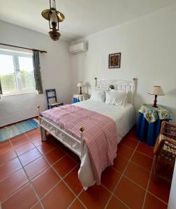 1 dormitorio con cama blanca y suelo de baldosa roja en Quinta do Cota, en Montemor-o-Novo