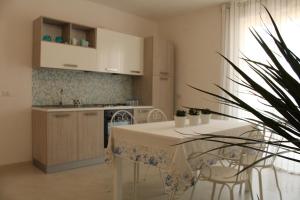 ポリニャーノ・ア・マーレにあるDimora Acquamarinaのキッチン(白いテーブル、テーブル、椅子付)
