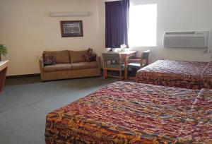 a hotel room with two beds and a couch and a table at Guardian Inn in Le Center