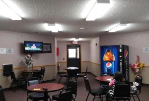 a waiting room with tables and chairs and a tv at Guardian Inn in Le Center