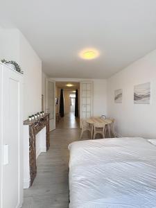 a white bedroom with a bed and a table at Spacieux appartement une chambre in Brussels