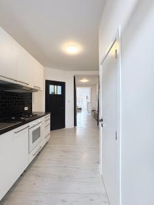 an empty kitchen with white cabinets and a hallway at Spacieux appartement une chambre in Brussels