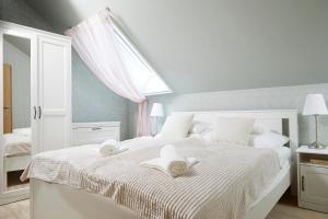 a white bedroom with two towels on a bed at Icce Borbirtok - Wine, Dine & Rest in Monoszló