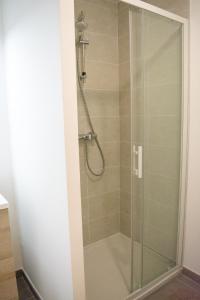 une douche avec une porte en verre dans une salle de bain dans l'établissement Les Tilleuls I, à Villeurbanne