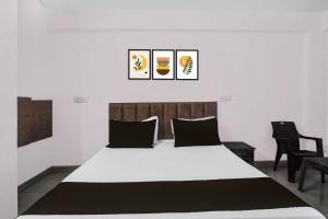 a bedroom with a large white bed with black pillows at Hotel O Shree Shyam Guest House in Noida