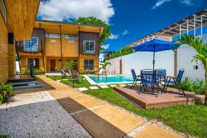 a patio with a table and umbrella next to a house at Macondo Ecolodge Alpinias - Veranera in Coco