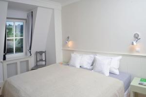 um quarto com uma cama com lençóis brancos e uma janela em Galerie Suites em Mariánské Lázně