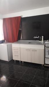 Eluisa في La Quebrada: مطبخ بدولاب بيضاء وستارة حمراء