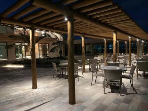 eine überdachte Terrasse mit Tischen und Stühlen sowie einem Tisch und Stühlen in der Unterkunft Brisa Muro Alto - Flat na Praia in Ipojuca