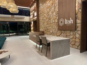 eine Lobby mit einer Steinmauer sowie einem Tisch und Stühlen in der Unterkunft Brisa Muro Alto - Flat na Praia in Ipojuca + 95 Fotos