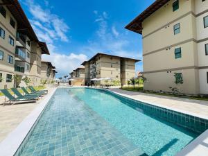 einem Pool vor zwei Gebäuden in der Unterkunft Brisa Muro Alto - Flat na Praia in Ipojuca