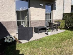 a patio with chairs and a table in a yard at L' Appart de Grand-Mère in Oudenburg