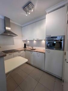 a kitchen with white cabinets and a stove top oven at L' Appart de Grand-Mère in Oudenburg