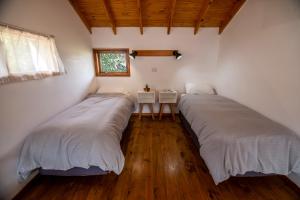 - 2 lits dans une chambre dotée de parquet et d'une fenêtre dans l'établissement Madre e Hija (refugio de montaña), à El Chalten