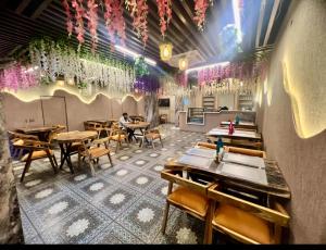 a restaurant with tables and chairs and flowers on the wall at Hotel Chelsea Plaza in Alīgarh