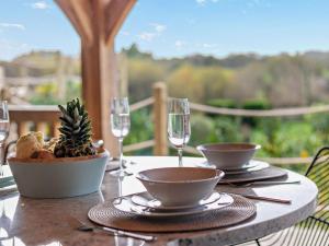 a table with two wine glasses and a bowl of pineapple at Rose Cottage in Saint Hilary