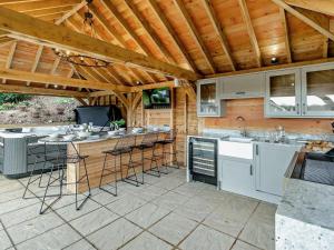 an outdoor kitchen with a bar with stools at Rose Cottage in Saint Hilary