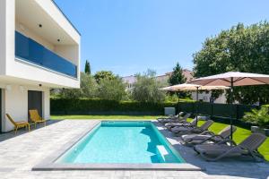 a pool with chairs and umbrellas next to a house at Villa Mila - NEW 2025 in Medulin +44 photos