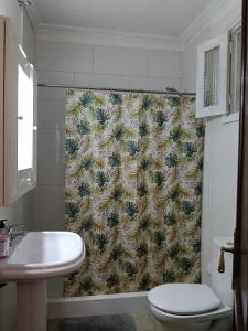 łazienka z zasłoną prysznicową, toaletą i umywalką w obiekcie Banana Surf House w mieście Los Cristianos