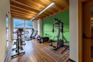 a gym with several tread machines in a room with green walls at Hotel Posta in Comano Terme